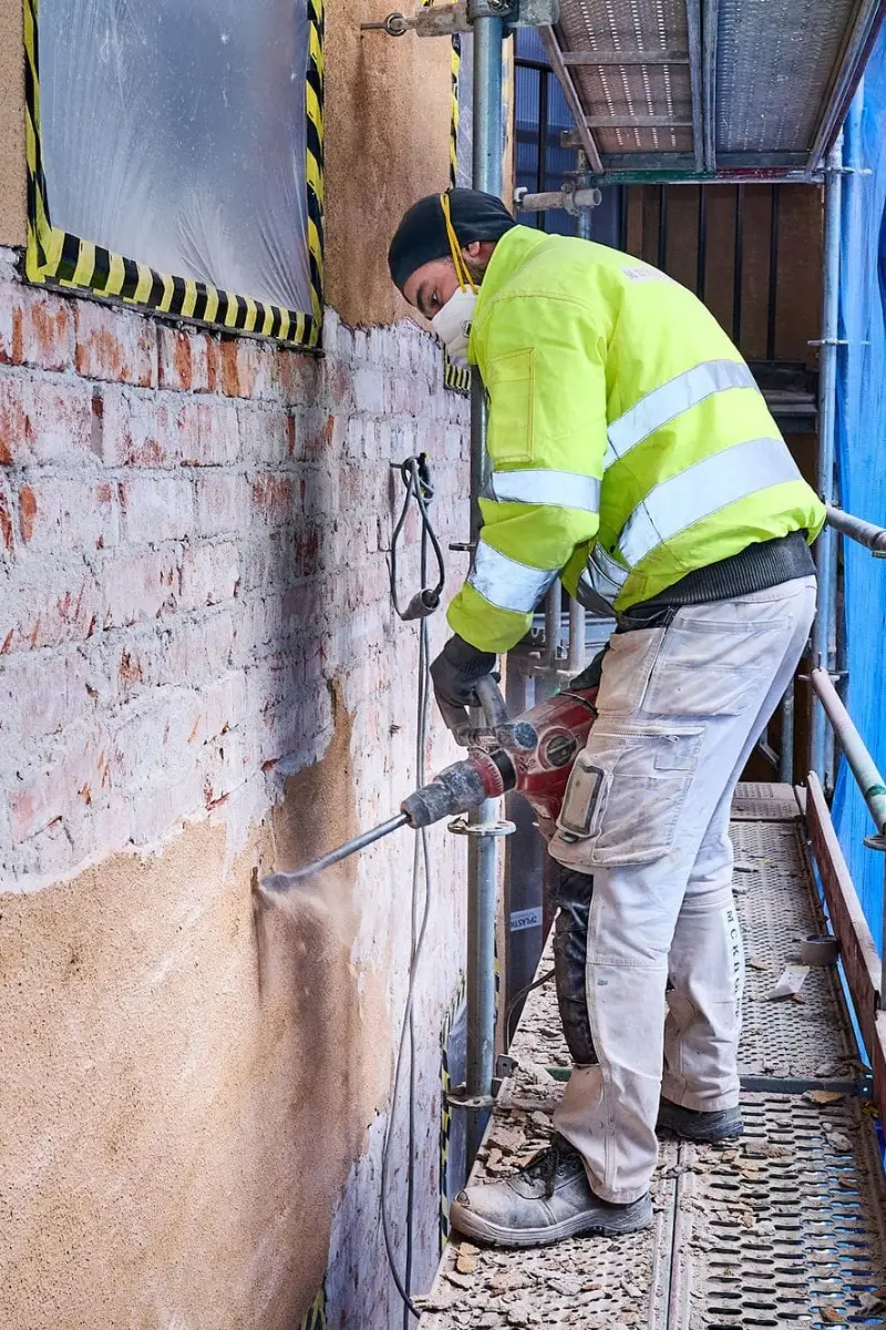 Hantverkare lagar tegelfasad från ställning under fasadrenovering