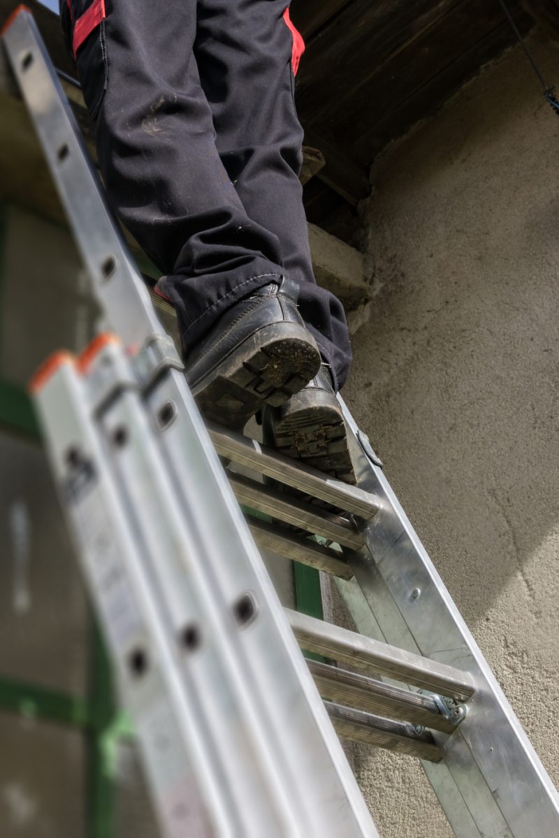 Texture, background, spring repairs, man uploaded on a folding ladder to repair the roof of an old rural house. Concept village.