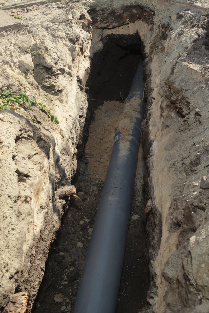 Installing sewer pipe in the ground trench. House sewer drain pipe installation