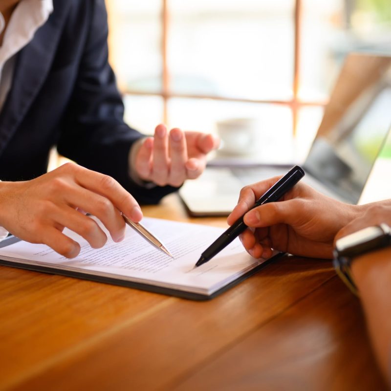 Closeup lawyer or insurance agent pointing at contract showing male client where to signature sign.