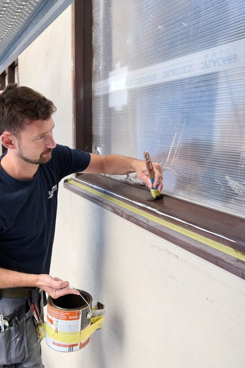 Målning av fönsterbåge från ställningen under fönsterrenovering